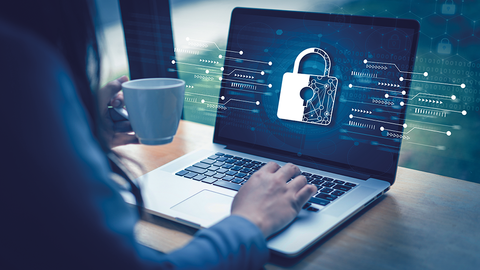 Für die HZD immer ein Thema: IT-Sicherheit gegen Cyberkriminalität Blick auf Schreibtisch mit Laptop und darüber gelegter Grafik aus Vorhängeschloss und Schaltplänen