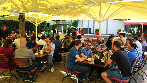 Sommerliches Get-Together: der D-Talk 2022 am HZD-Standort Hünfeld Gäste des D-Talk 2022 in Hünfeld, die unter gelben Sonnenschirmen in einen Biergarten sitzen