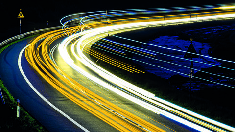 Management-Tool MIS der HZD – reibungsloser Datenverkehr für das Digitale Lagebild – K Nachtaufnahme einer Straße in Langzeigbelichtung, bei der die Scheinwerfer der fahrenden Autos als farbige Lichtbalken zu sehen sind