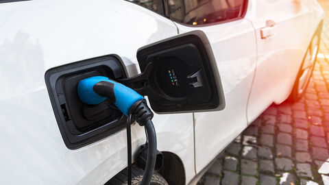 Einfacher zu Strom für E-Autos – mit der von dual Studierenden der HZD entwickelten Buchungs-App Close-up auf Ladepunkt eines weißen Autos, in dem ein blaues Ladekabel steckt