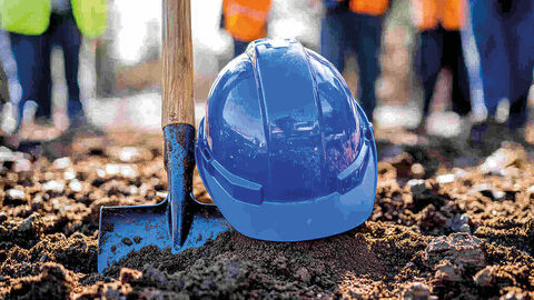 Beginn einer neuen Partnerschaft: Spatenstich für das Rhöncloud Rechenzentrum in Eichenzell Close-up auf einen in der Erde steckenden blauen Spaten, daneben ein Schutzhelm in demselben Blau